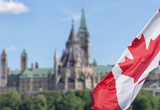 Canadian flag flying with Parliament Hill in the background
