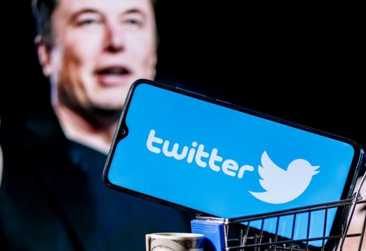 Musk with Twitter on a phone in a cart