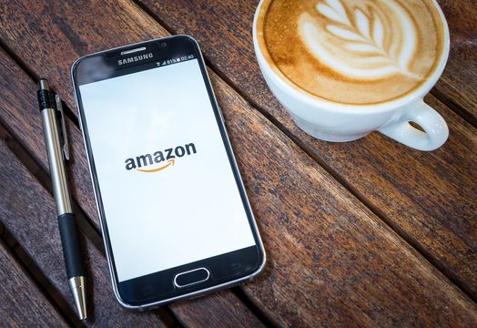 Samsung Galaxy S6 with amazon app on the screen on Wood desk office.