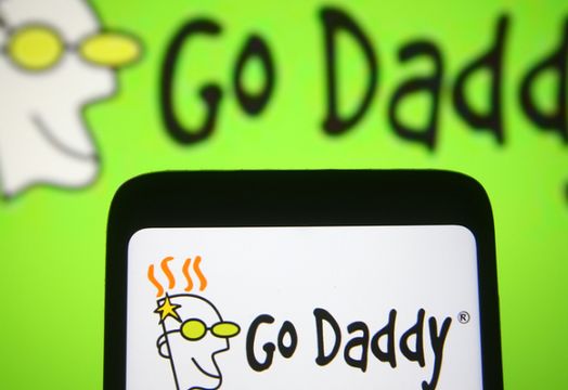 GoDaddy on a phone in front of GoDaddy logo